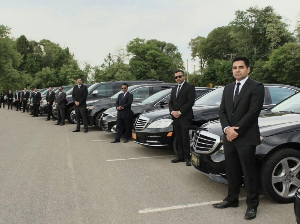 20 suit-wearing chauffeurs in line of 20 high-end transportation vehicles
