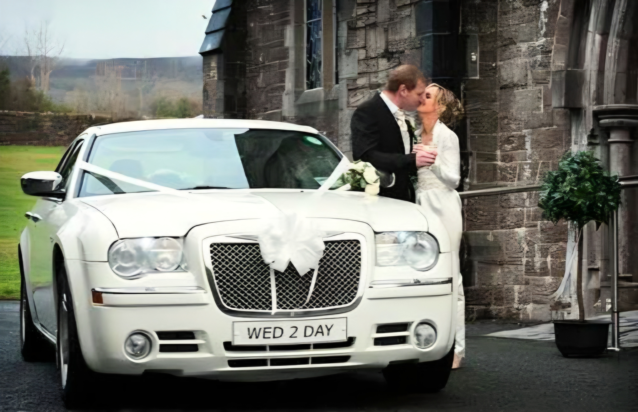 Beautiful Bride and Groom  standing and kissing next to their Luxurious white Bridal Car
