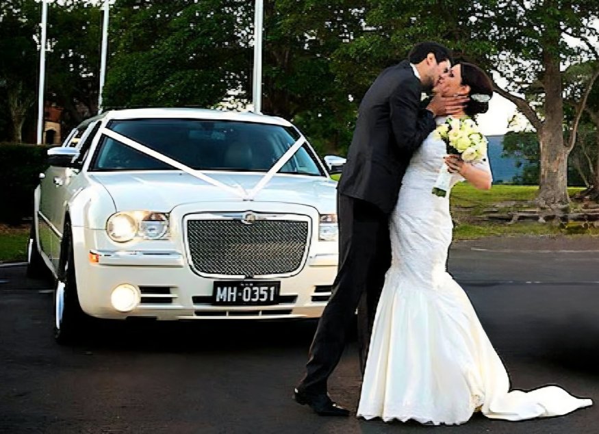 Loving Groom in Passionate Kiss with Adoring Bride by their Extraordinary sleek white Bently Bridal Car 